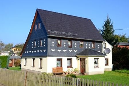 Freistehendes Einfamilienhaus mit weißer Fassade im Erdgeschoss und Rasen rundherum