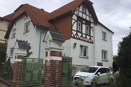 Zweifamilienhaus mit Fachwerkelementen und leicht verwitterter, mintgrüner Fassade