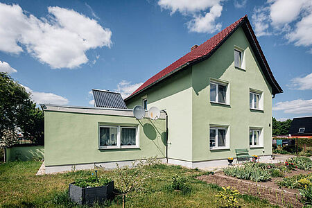 Dreistöckiges Wohnhaus mit ebenmäßiger Fassade in Pastellgrün
