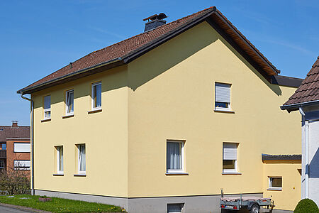 Mehrfamilienhaus mit frischer Fassade in sonnigem Gelb