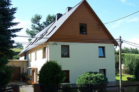 Weißes Wohnhaus mit vertäfelter Fassade des Dachgeschosses