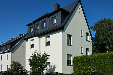 Schmales Reihenhaus mit spitzem Satteldach und sehr heller pastellgrüner Fassade