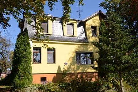 Villa mit gelb gestrichener Fassade und orangenem Fundament