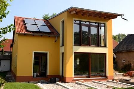 Wohnhaus mit kubistisches Elementen, orangener Fassade und Photovoltaikanlagen
