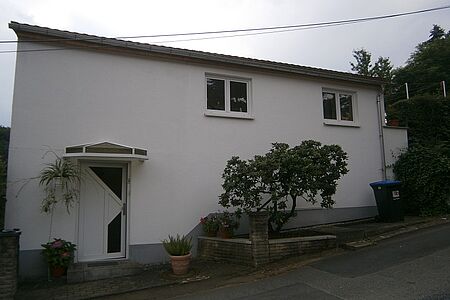 Weißes Bungalow mit Flachdach vor der Fassadensanierung