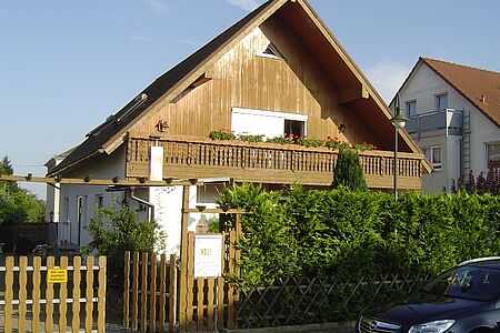 Einfamilienhaus mit weißer Fassade und hellbrauner Vertäfelung im Obergeschoss