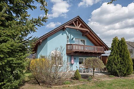 Babyblaues Wohnhaus mit Holzbalkon