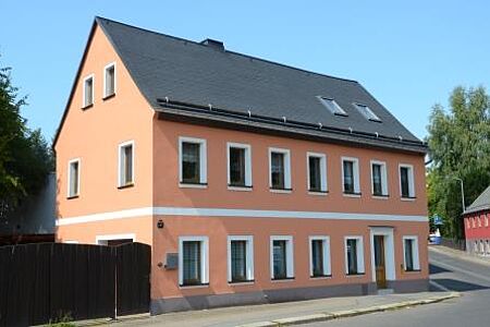 Saniertes Haus mit pastellfarbener Fassade und weißen Akzenten an Fenstern