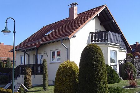 Weißes Einfamilienhaus mit Treppenaufgang und Balkon