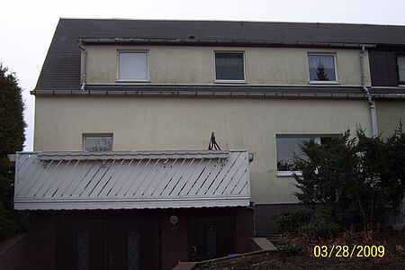 Beiges Reihenhaus mit schmutziger Fassade vor der Sanierung