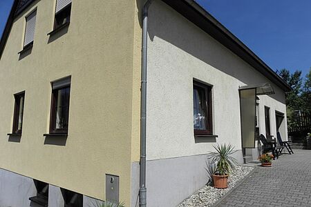 Dreistöckiges Haus mit verschmutzter Fassade in Gelb-, Weiß- und Grautönen