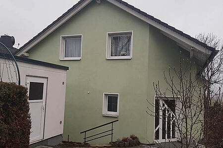 Einfamilienhaus mit leicht ergrauter, hellgrüner Fassade vor der Sanierung