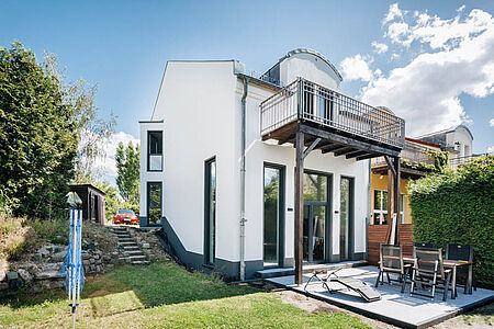 Modernes weißes Wohnhaus mit Terrasse, Balkon und hohen durchgängigen Fenstern