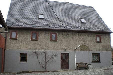 Mehrfamilienhaus mit veralteter Fassade und Pflanzenbewuchs