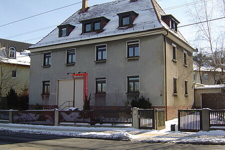 Graues Mehrfamilienhaus mit alter Fassade