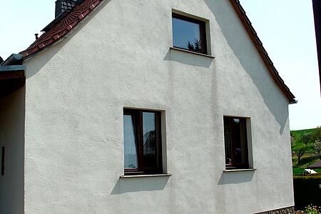 Weißes Einfamilienhaus mit verwitterter Fassade