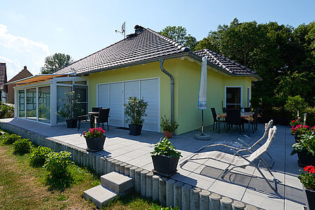 Bungalow mit Walmdach und knallig gelber Fassade