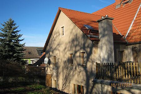 Verwinkeltes Wohnhaus mit matter, dunkelgelber Fassade 