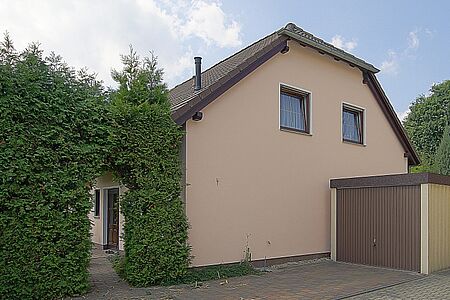 Wohnhaus mit Krüppelwalmdach und pfirsichfarbener Fassade