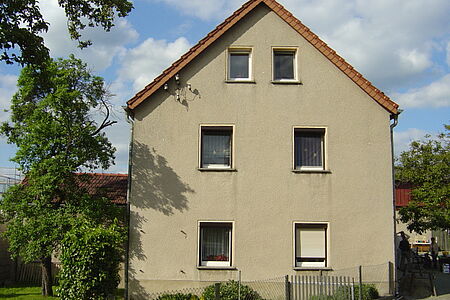 Dreistöckiges Wohnhaus mit hellgrauer Fassade