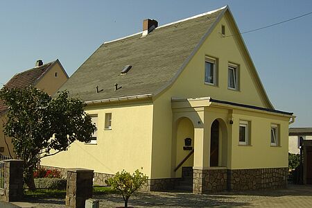 Gelbes Haus mit Vorbau und überdachtem Treppenaufgang