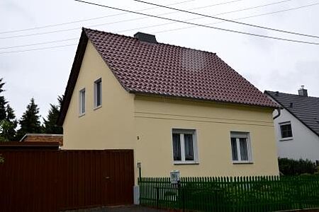 Einfamilienhaus mit frischer, gelber Fassade und roten Dachziegeln