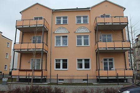 Orange gestrichenes Mehrfamilienhaus mit Anbaubalkonen