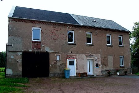 Haus mit alter Fassade, teils sichtbaren Ziegeln und hölzernem Garagentor