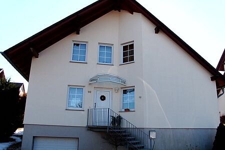 Einfamilienhaus mit weißer Fassade und Garageneinfahrt im Souterrain