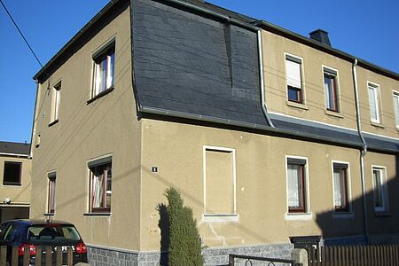 Verblichene Hauswand mit mehren witterungsbedingten Schäden 