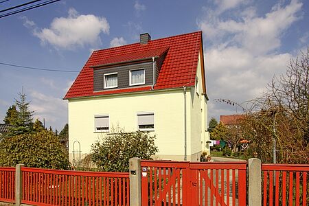 Großes Einfamilienhaus mit rotem Satteldach und frischer Fassade in hellem Mintgrün