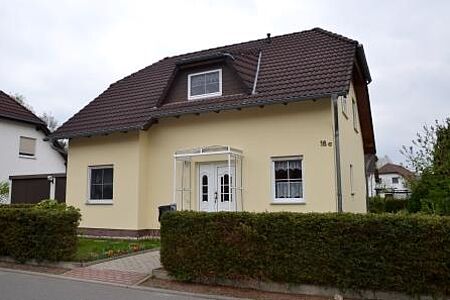 Hellgelbes Einfamilienhaus nach der Fassadensanierung