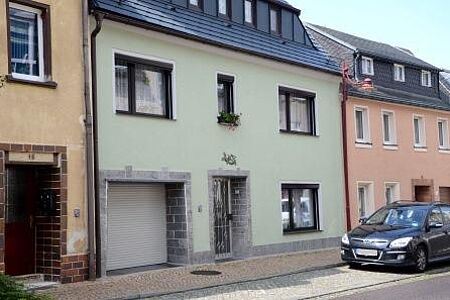 Reihenhaus mit weißgrüner Fassade und kleiner Garage neben Hauseingang