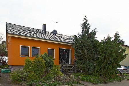 Vorher mit Pflanzen bewachsenes Wohnhaus nach der energetischen Sanierung