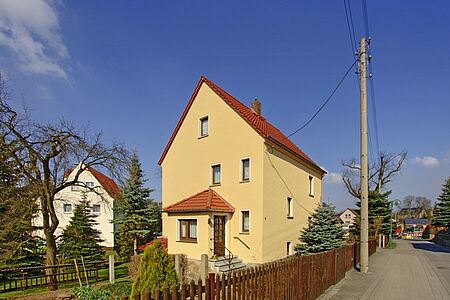 Dreistöckiges, schmales Einfamilienhaus mit ebenmäßiger, pastellgelber Fassade 