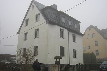 Schmales Reihenhaus mit Grünspan auf der weißen Fassade