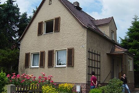 Einfamilienhaus mit altem Putz und braunen Fensterläden