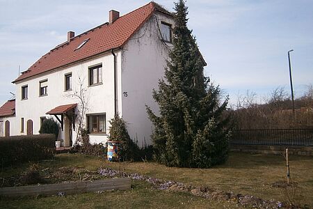 Mehrfamilienhaus mit weißer, bewachsener Fassade