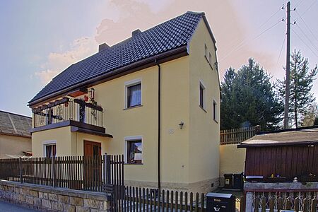 Dreistöckiges Wohnhaus mit Walmdach und ebenmäßigem, pastellgelbem Anstrich