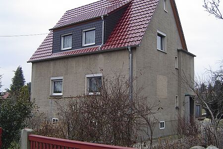 Großes braun verputztes Einfamilienhaus ohne Anstrich vor der Fassadensanierung