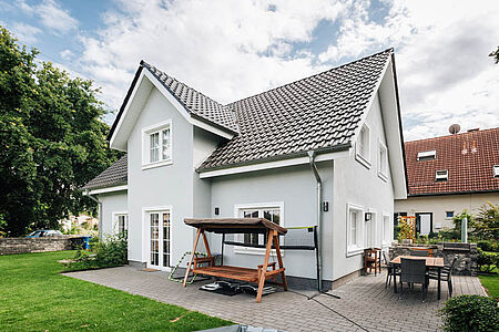 Einfamilienhaus mit ebenmäßiger taubenblauer Fassade und weißen Fenster- und Türrahmen