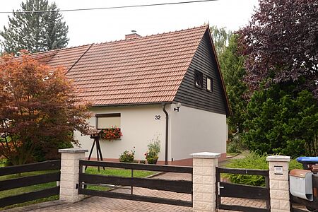 Gartentor zu einem Haus mit weißer Fassade und hölzener erster Etage