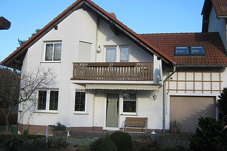 Weißes Haus mit Balkon vor der Fassadensanierung