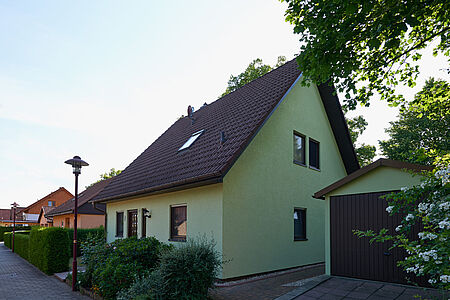 Kleines Wohnhaus mit spitzem Satteldach und strahlend grüner Fassade