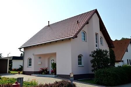 Einfamilienhaus mit eingefasstem Eingangsbereich und blass rötlicher Fassade