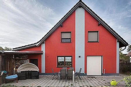 Knallrotes Wohnhaus mit hellgrauen Elementen auf der Fassade