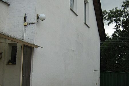 Einfamilienhaus mit sanierungsbedürftiger Fassade in schmutzigem Weiß