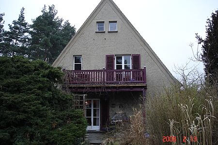 Graues Haus mit spitzem Dach und Balkon