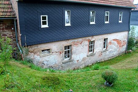 Dreistöckiges Wohnhaus mit baufälliger Fassade im Erdgeschoss