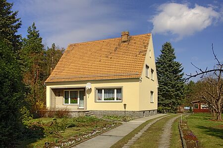 Kleines Wohnhaus mit Grünen mit pastellgelber Fassade